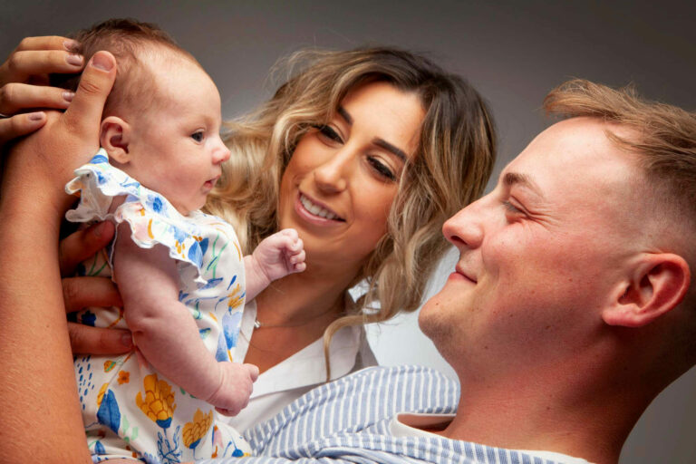 mum and dad holding daughter smiling