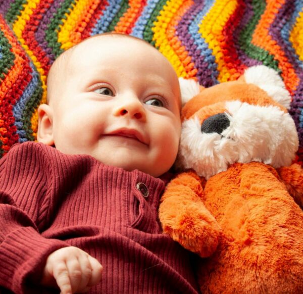 photo of a smiling baby with teddy