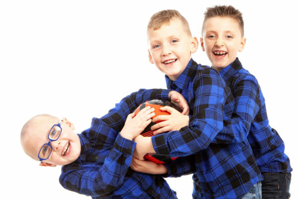 three boys holding a football smiling