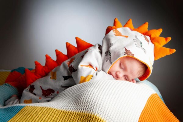 photo of a sleeping boy in dinosaur outfit